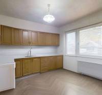 A family house kitchen with brown cabinets, white walls, and a wooden decor floor.