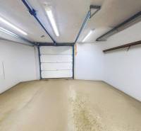 The garage in the family house has white walls, lights, and elevated storage space.
