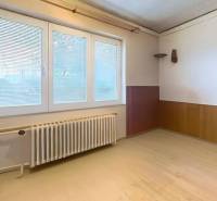 Room in a family house with a light wall, window, and wood-decorated floor.