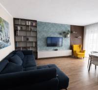 Living room with a blue sofa, a yellow armchair, and a wooden decor floor in a three-room apartment.