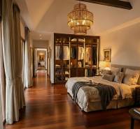 Stylish bedroom in a villa with wood-patterned flooring and an open wardrobe.