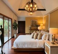 Luxury bedroom in a villa with wood-patterned flooring and large windows.