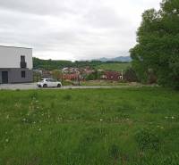 Plots - housing in Žilina on Chotárna show a green meadow with a modern building and a car.