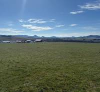 Plots - living in Stránske on Borie Street. A vast green meadow with a mountain backdrop.