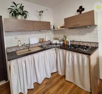 A kitchen in a 3-room apartment with a wooden decor floor and a gas stove.