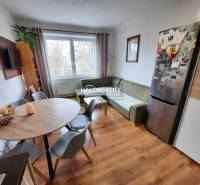 Living area in a 3-room apartment with a wood-patterned floor and a dining table.
