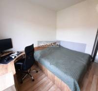 A bedroom with a desk and wooden decor flooring in a 3-room apartment.