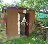 A small garden shelter next to a stone wall in the garden of the Goncruszka family house.