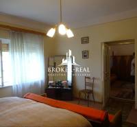 Bedroom in a family house with a wooden decor floor, bed, armchair, chairs.