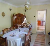 A dining room in a family house with wooden furniture, a table, chairs, and a ceiling lamp.