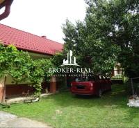 The garden of the family house in Goncruszka with a red roof and a car on the lawn.