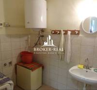 Bathroom with tiles, sink, water heater, and mirror in a family house.