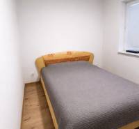 Bedroom in a 2-room apartment with a bed and a floor with a wooden decor.