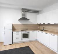 White kitchen, light decor, appliances and wooden decor flooring in a 2-room apartment.