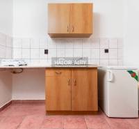 Kitchen area with tiles, cabinets, and a small refrigerator in hotels and guesthouses.