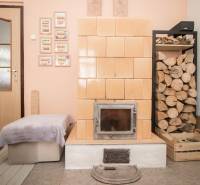 Brick fireplace with wood, door, and ottoman in the interior of a family house.