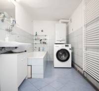 A bathroom in a family house with a bathtub, sink, washing machine, and ladder radiator.