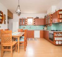 A kitchen in a family house with light furniture, ceramics, and a floor with a wooden decor.