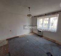 A room with a carpet, white walls, and a large window, suitable for renovation; Residential land.
