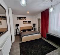 A bedroom in a family house with a mirror, red curtains, and wall decorations.