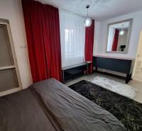 The interior of a family house with red curtains, a mirror, and a dark carpet.