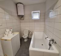 Bathroom in a family house with a bathtub, washing machine, boiler, and toilet.
