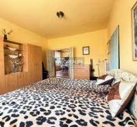 A bedroom in a family house with a bed featuring a leopard pattern and a wardrobe with a wood decor.
