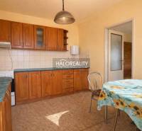A kitchen in a family house with built-in cabinets and a table with a floral tablecloth.