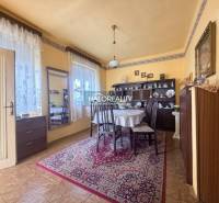Dining room in a family house with a wooden decor floor, decorated carpet, and a table.