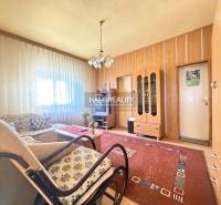 Living room in a family house with light from the window, wooden wall decor, and furniture.