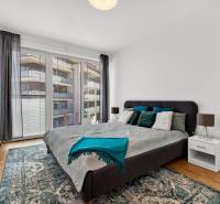 A bedroom with a large bed, balcony doors, and a wooden decor floor in a 2-room apartment.