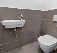 Bathroom with a sink and toilet in a 2-room apartment with simple tiles.
