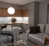 A kitchen in a 2-room apartment with a wooden decor floor and a round table.