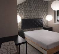 Bedroom with a bed, evening lighting, table, and chair in a two-room apartment.