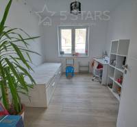 Children's room in a family house with a bed, table, and shelf on a floor with a wooden decor.