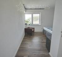 A room in a family house with a floor with a wooden decor, an armchair, and a window.