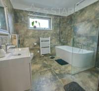 A bathroom with a glass shower enclosure and a bathtub in a family house.