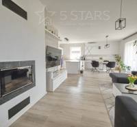 Living room with a fireplace, TV, and wood-patterned flooring in a family house.