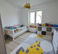 Children's room with a bed, toys, a giraffe-themed rug, and a wooden decor floor.