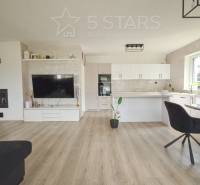 Living room with kitchen in a family house, light walls, floor with wooden decor.