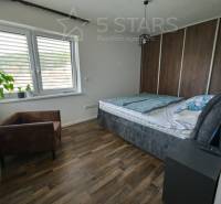 Bedroom in a family house with a bed, chair, and floor with wood decor.