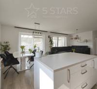 The interior of a family house with a wooden decor floor, white walls, and black furniture.