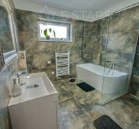 Bathroom with a bathtub, shower, and tiles in a family house.