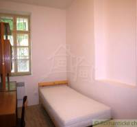 Simple bedroom with a single bed and wooden furniture in a family house.
