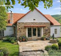 A family house in Dobroč with stone elements, surrounded by a well-maintained garden and trees.