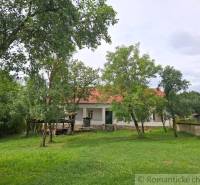 A family house in Dobroč with a white facade and a red roof, surrounded by greenery.