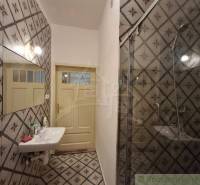 Bathroom with a tiled wall, mirror, sink, and shower in a family house.