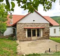 A family house in Dobroč with a stone facade, traditional roof, and a pleasant garden.