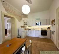 A kitchen with white furniture and a wooden decor floor in a family house.