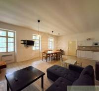 Living room with kitchen in a family house, wooden decor flooring, dining table, sofa.